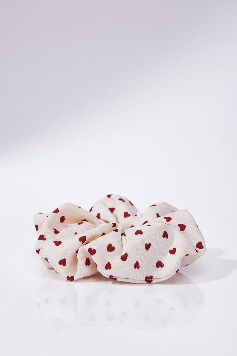 Amour Scrunchie auf heller Oberfläche mit zartem Pastell-Violett-Lichtschimmer im Hintergrund