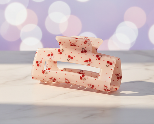 Coquette Cherry Clip auf Marmor mit pastell-lila Lichtschimmer