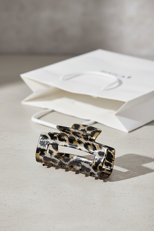 Square Onyx Clip auf hellgrauer Steinfläche mit weißer Boutique-Papiertasche im Hintergrund