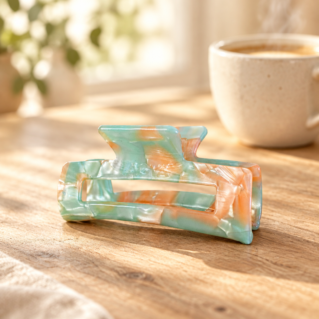 Retro Sorbet Haarklammer in Mint und Orange auf hellem Holztisch mit Kaffeetasse im Hintergrund
